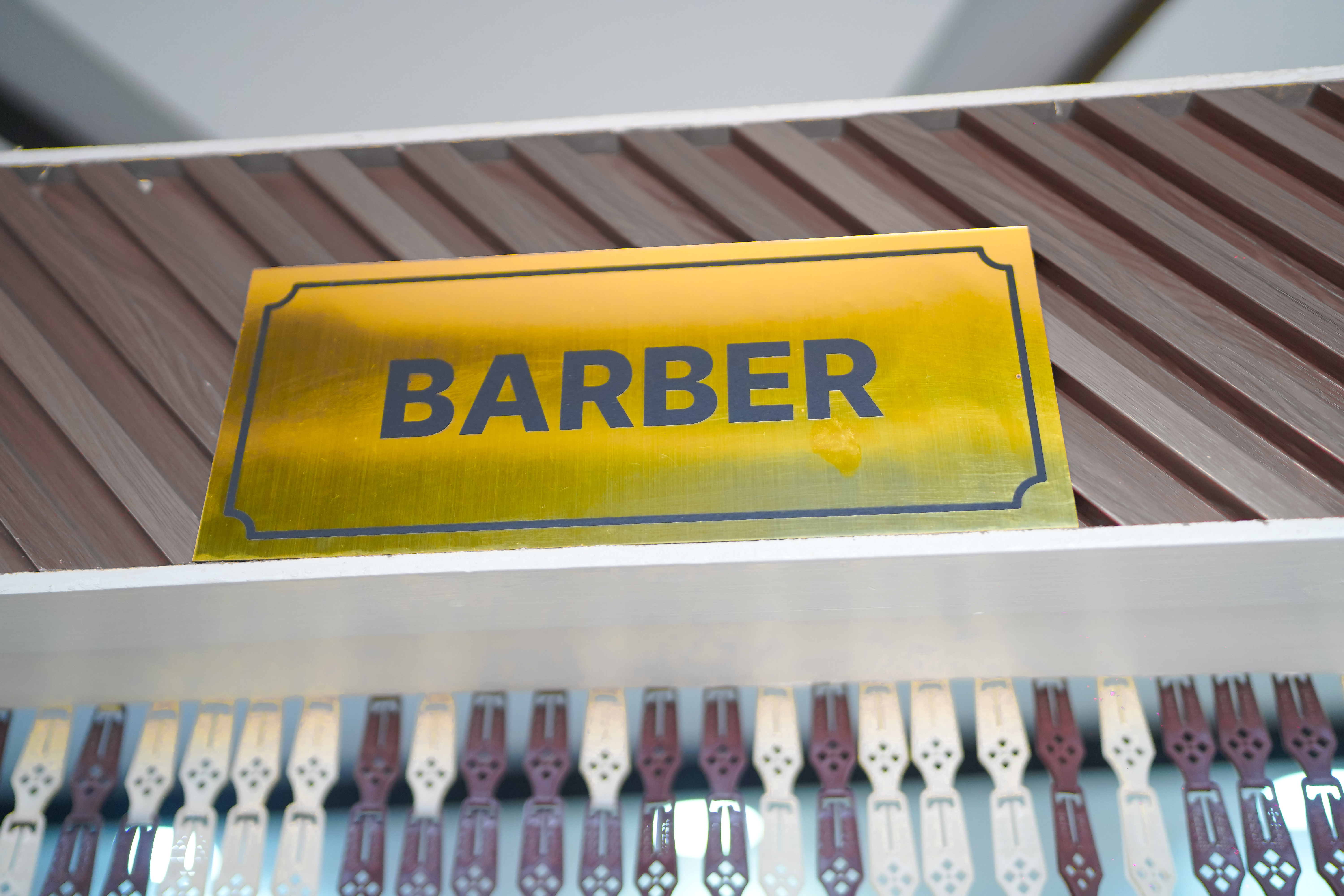 Gold BARBER plaque on wooden slat wall