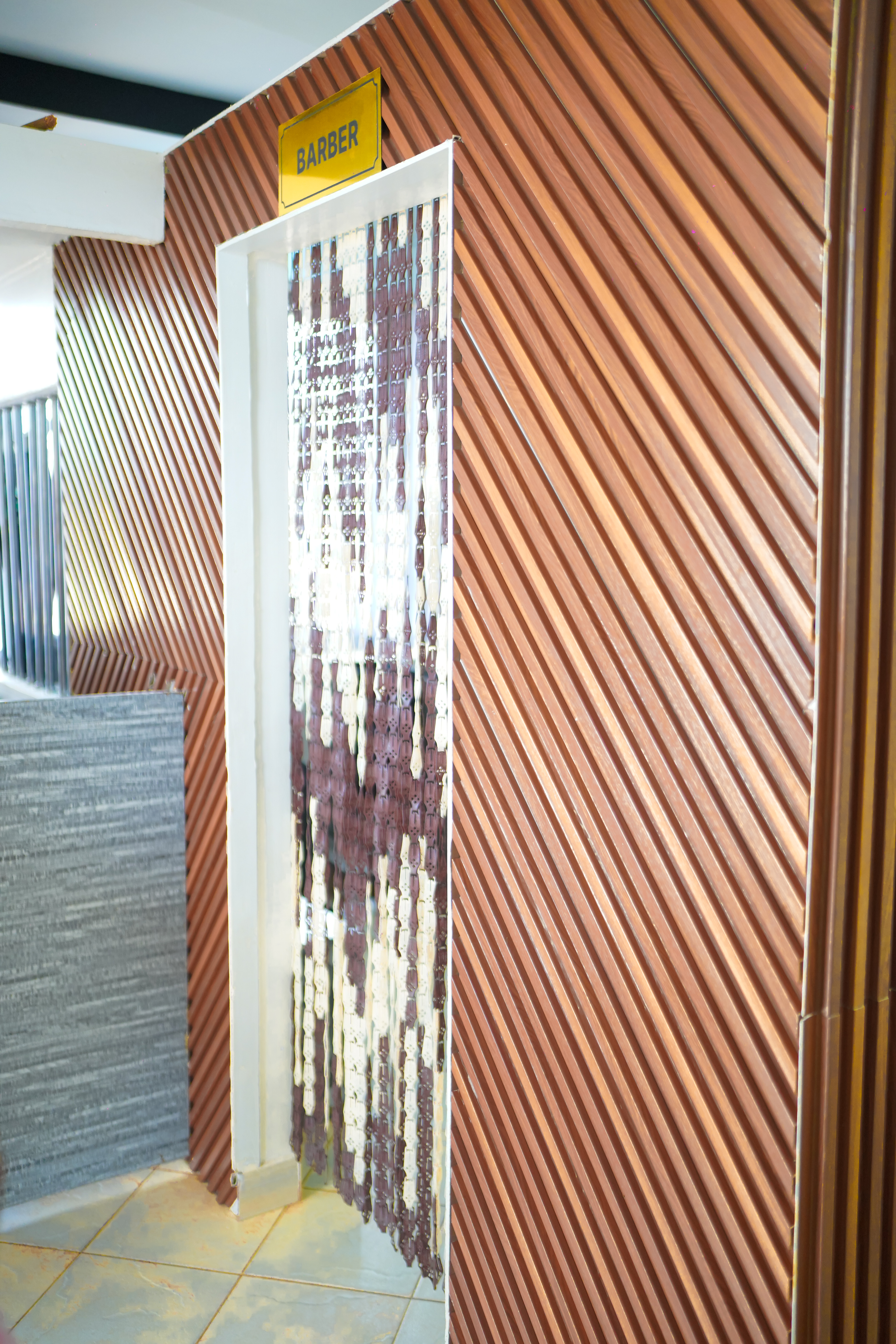 Barber entrance — dark walnut slat wall panelling