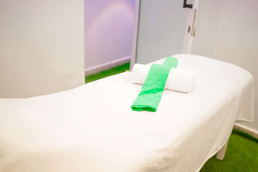 Clean white massage table with green towels
